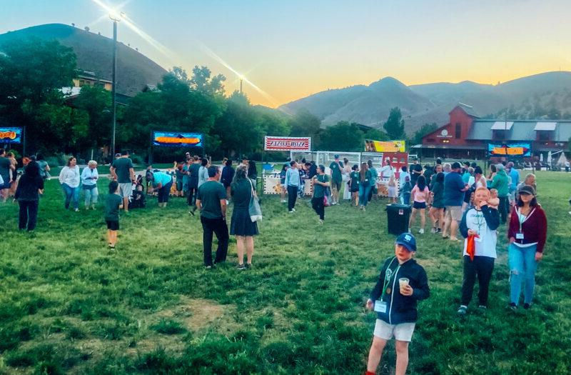 A crowd of people in a grass field at flok Family Camp West in 2023.